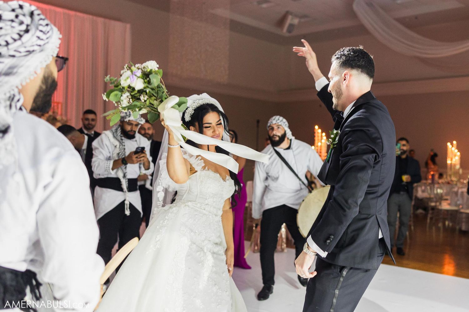 Newlyweds dancing energetically with guests at their wedding reception.