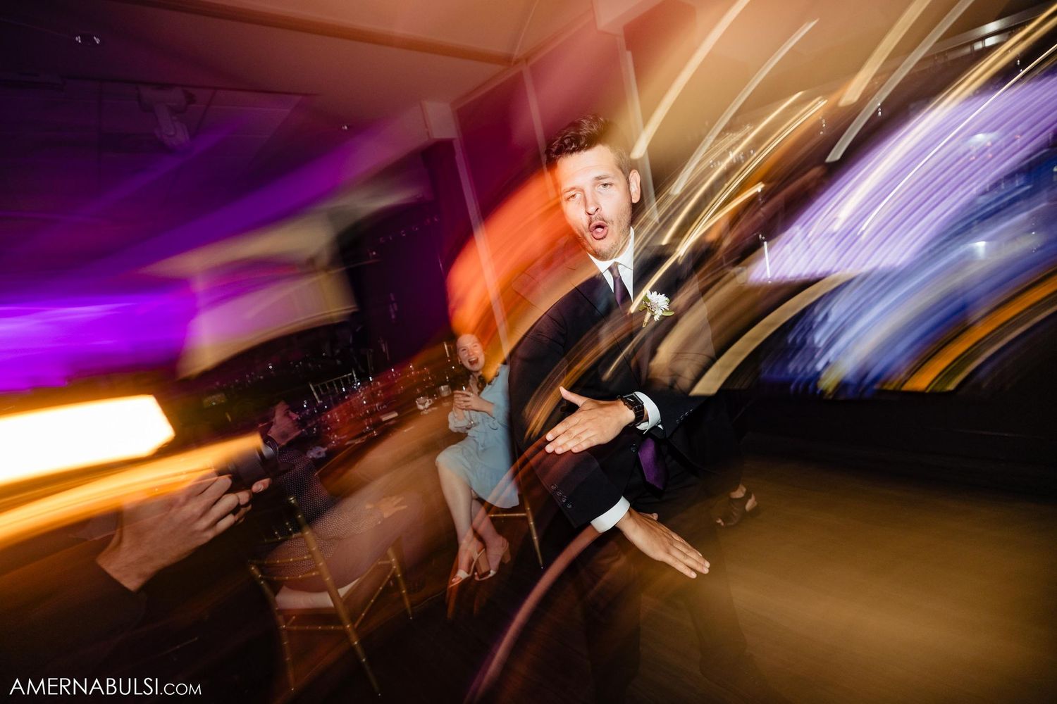 Dynamic photo with light trails capturing energetic dancing at wedding reception.