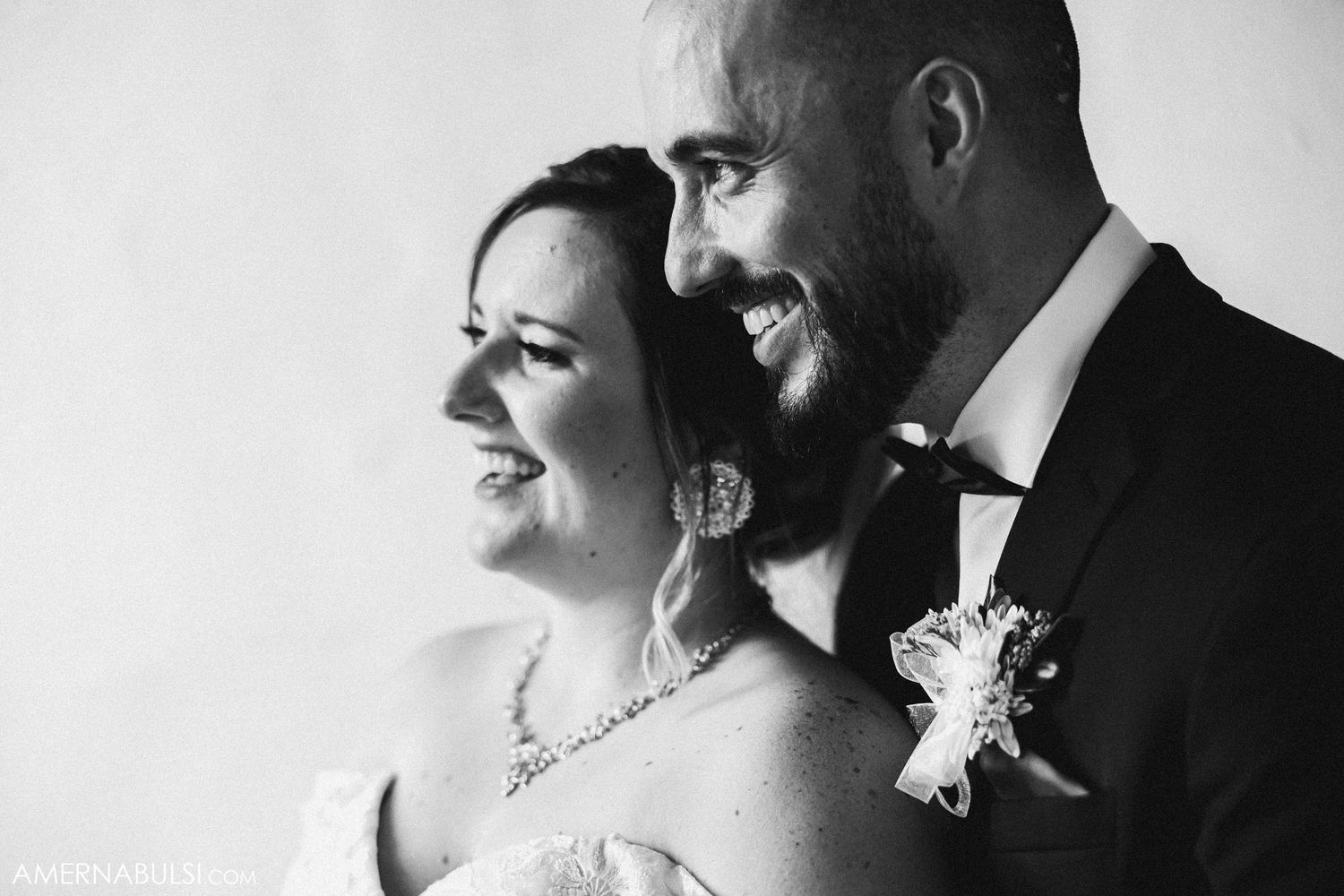 Black and white candid wedding portrait capturing joyful laughter.