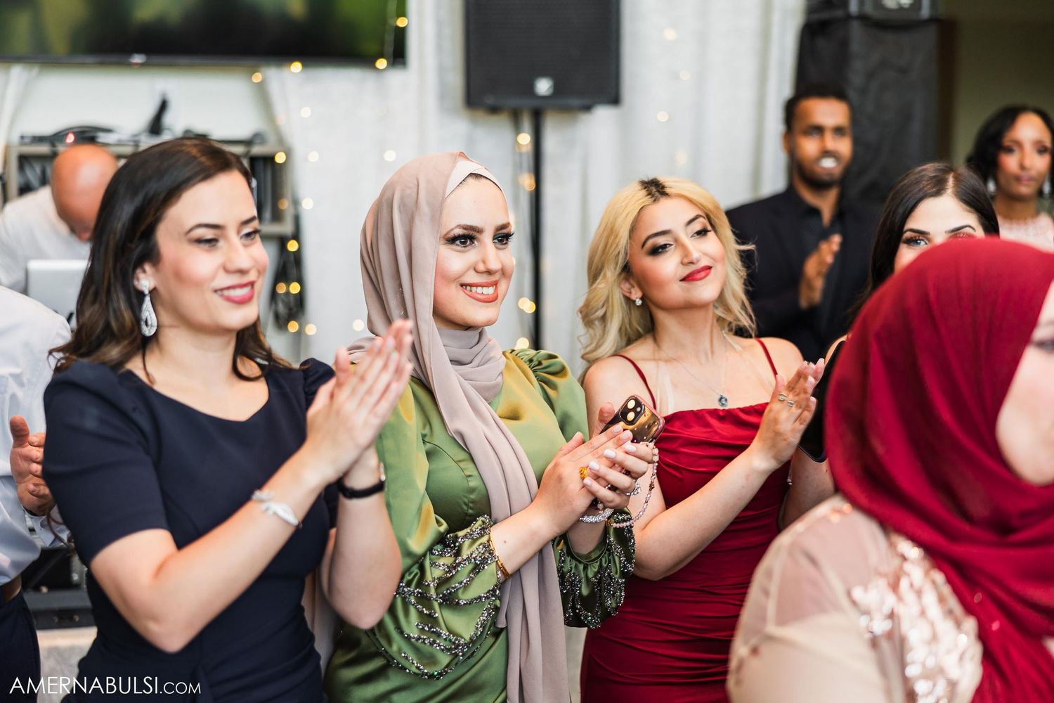 Wedding guests clap and celebrate during reception festivities.