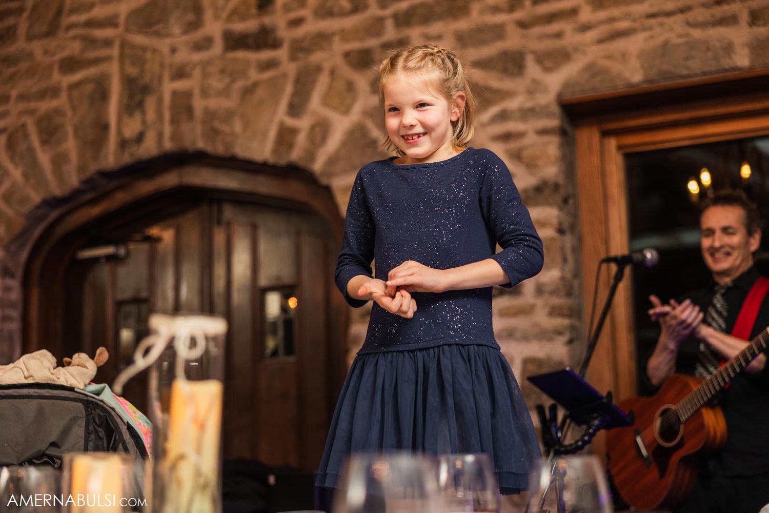 A young performer in a navy blue dress entertains guests at a wedding reception.