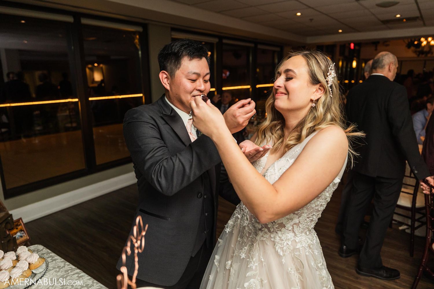 A couple playfully sharing cake at their wedding reception.