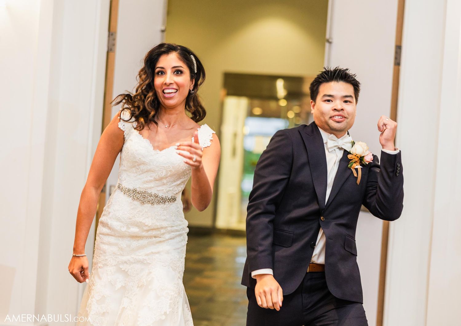 Newlyweds show excitement while running through venue hallway after ceremony.