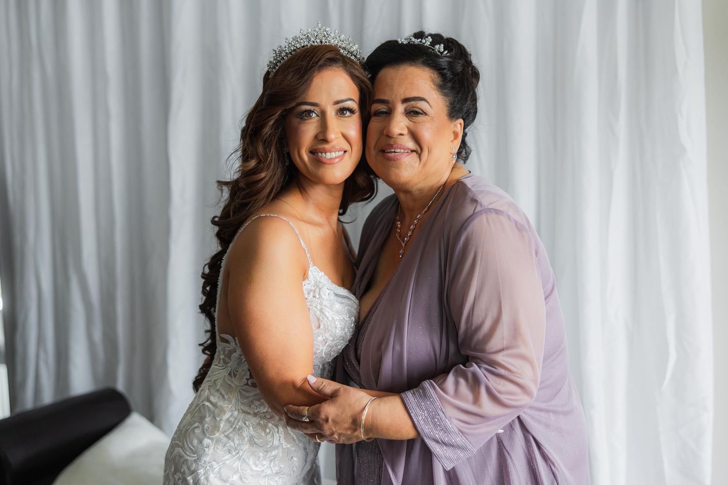 A heartwarming pre-wedding moment captured against white curtain backdrop.