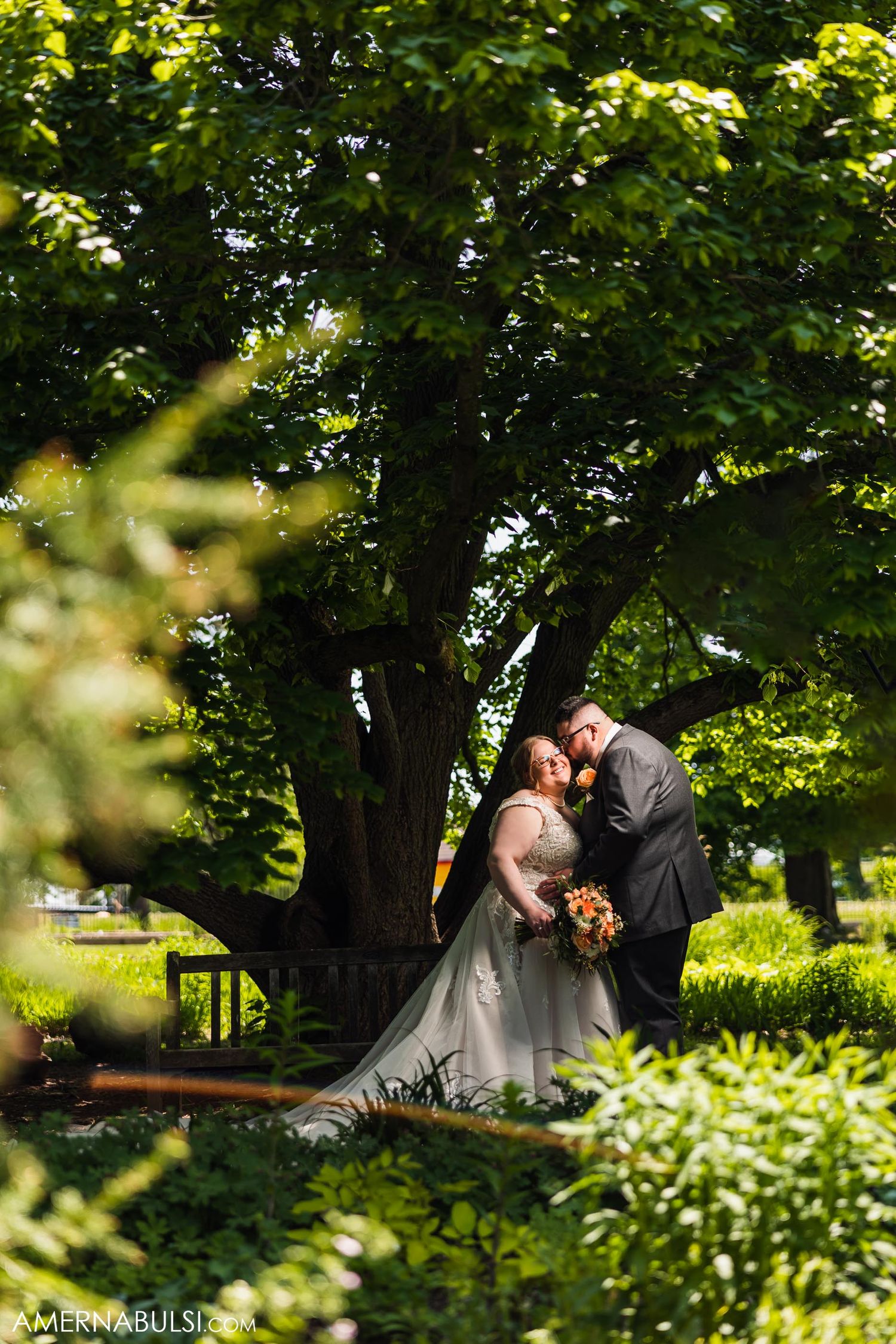 Romantic garden wedding photo with couple framed by lush summer greenery.