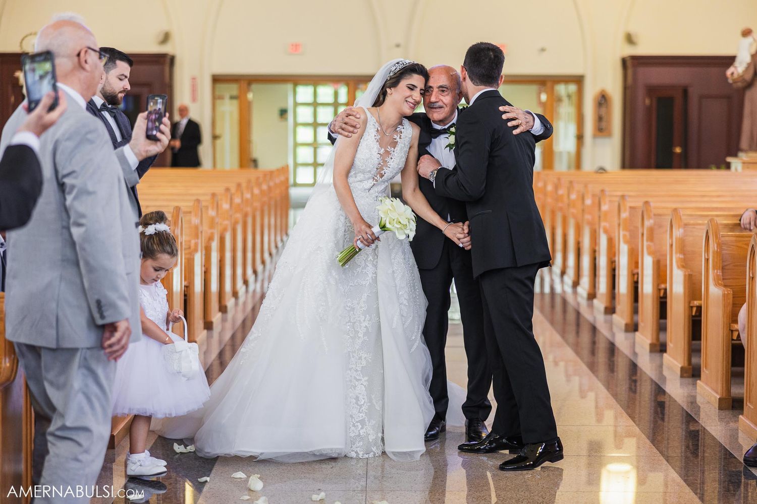 A wedding ceremony takes place in a bright church interior with traditional wooden pews.