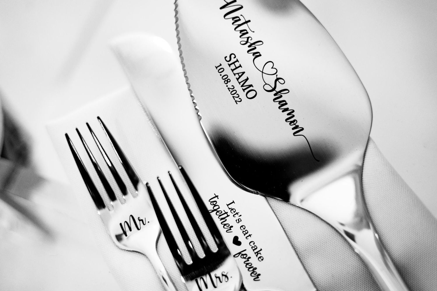 Black and white close-up of elegant silverware with custom wedding engraving.