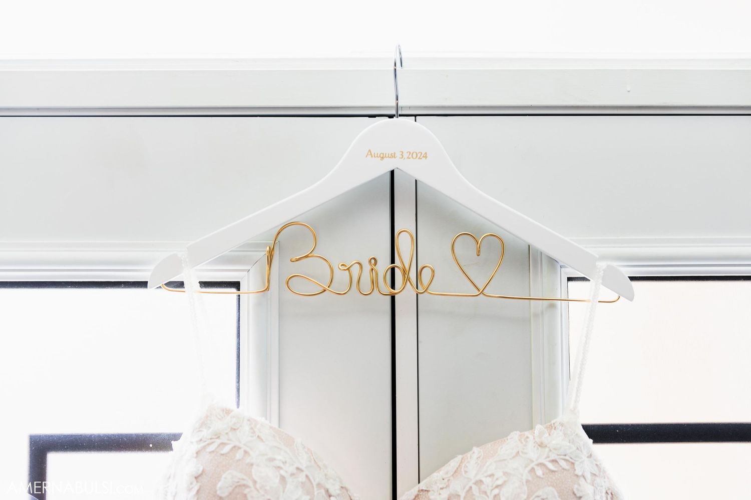 A wedding dress hanging with a golden 'Bride' sign displayed at the top.