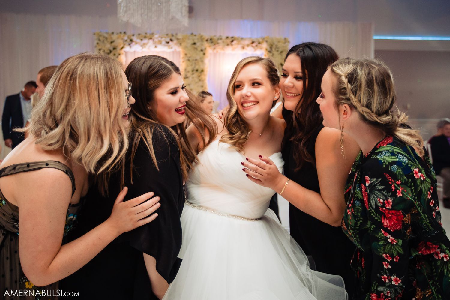 Joyful celebration moment with friends sharing laughter and embraces at a wedding reception.