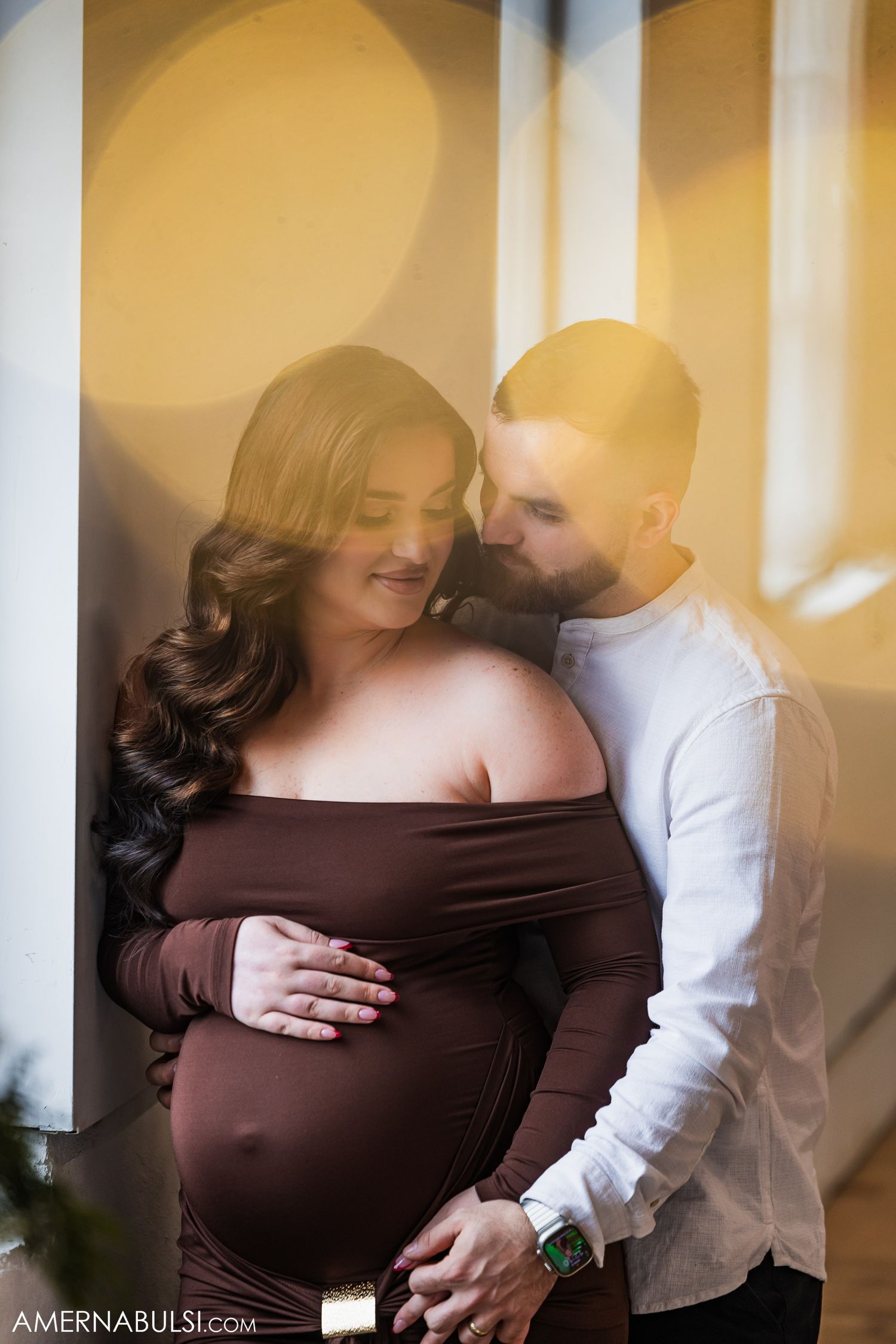 A couple standing by the window cuddling