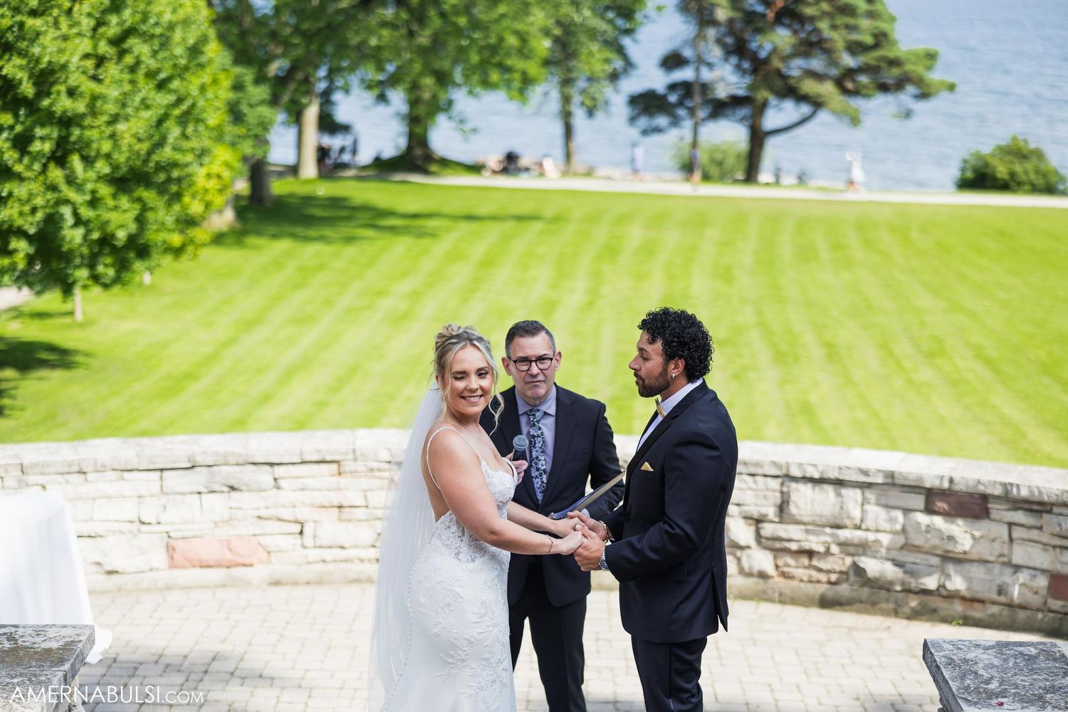 Wedding ceremony taking place on a stone patio with rolling green hills in the background.