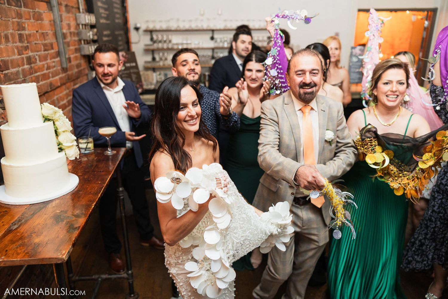 Wedding party celebrating with cake and festive decorations in an industrial-style venue.