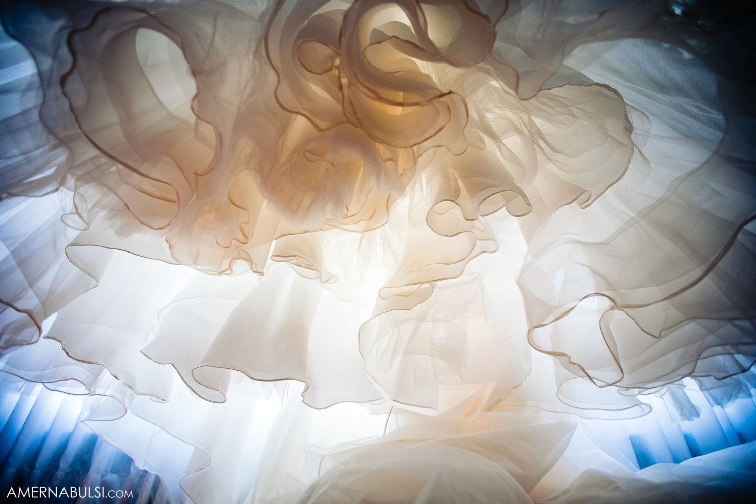Close-up details of a wedding dress layers creating ethereal patterns in soft lighting.