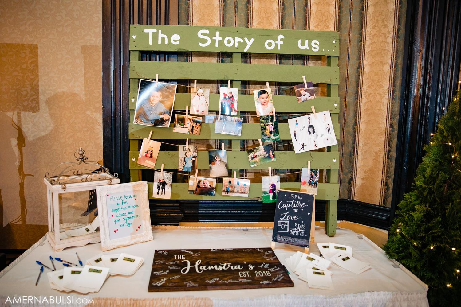 Wedding photo display area with string lights and personal photos arranged on rustic boards.