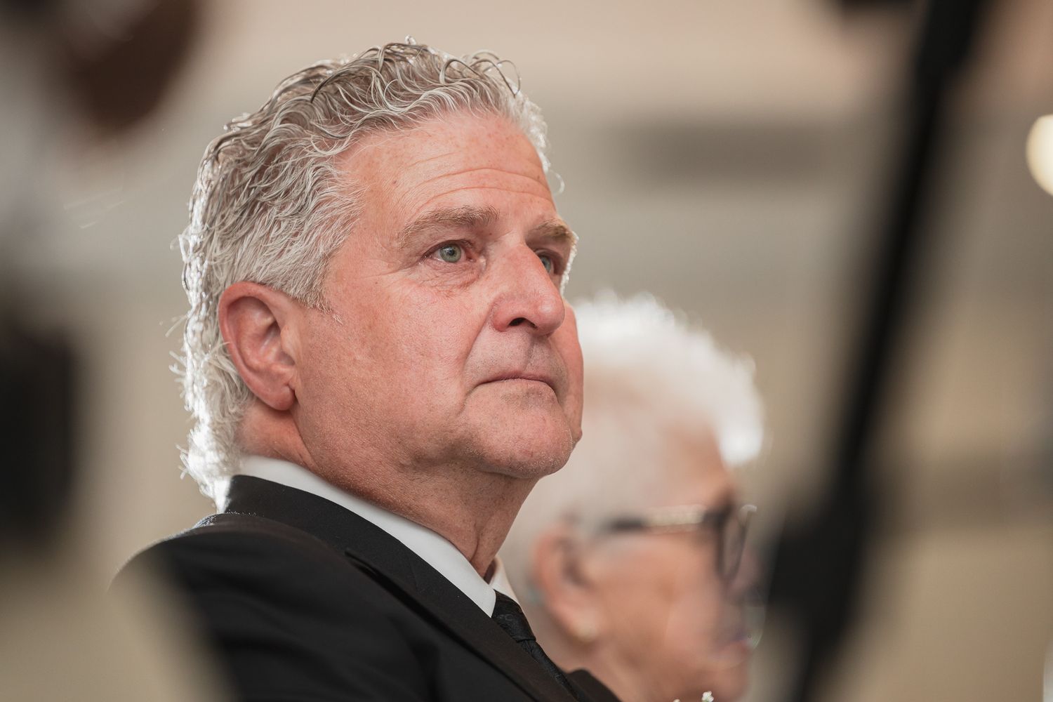 Distinguished older man with silver hair in formal black attire attending an elegant event.