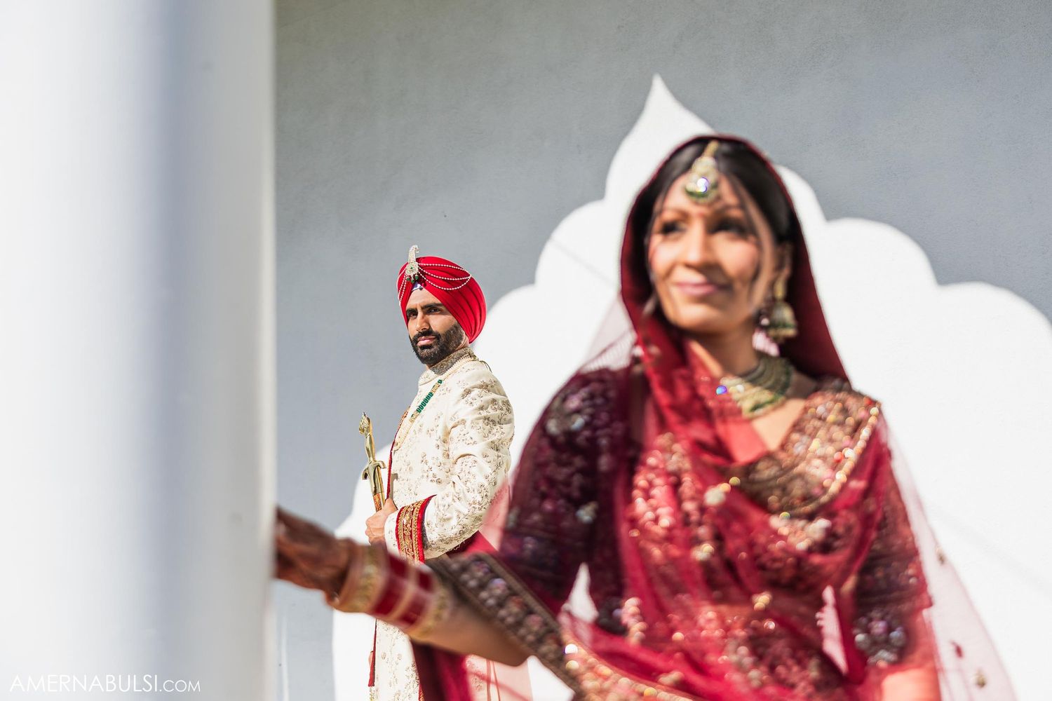 Traditional Indian wedding couple photographed against white architectural elements.