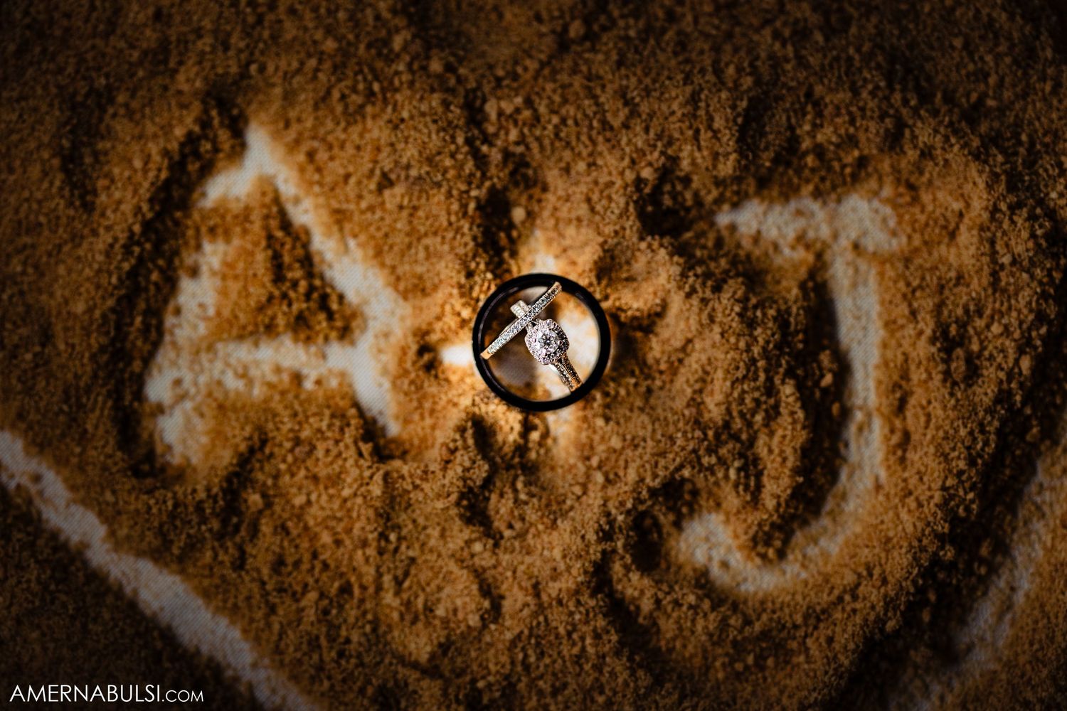 Close-up details of wedding rings creating heart shadows on textured golden surface.