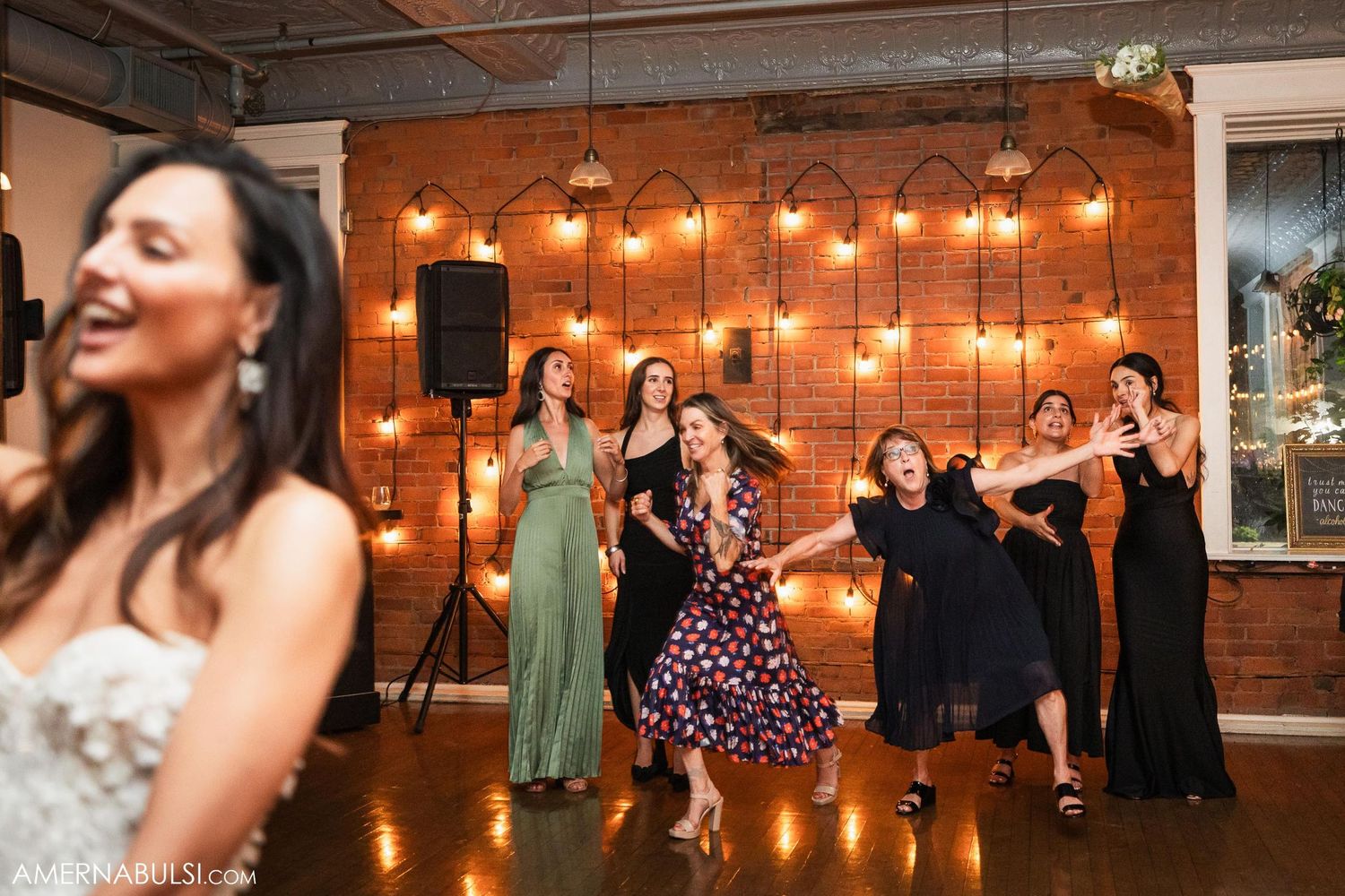 Wedding celebration with string lights and dancing in an industrial-style venue.
