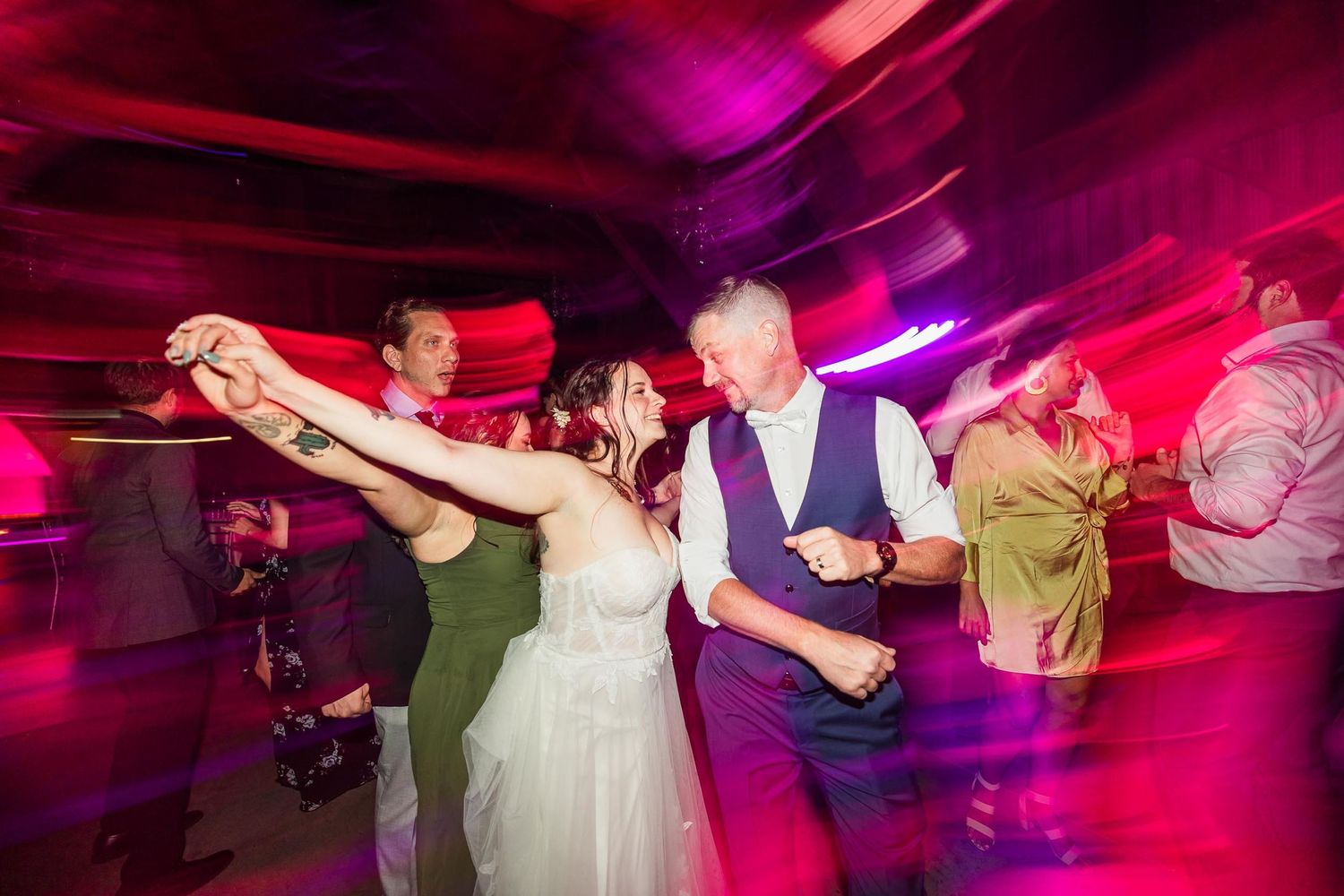 Wedding reception guests dancing together under dramatic red lighting effects.