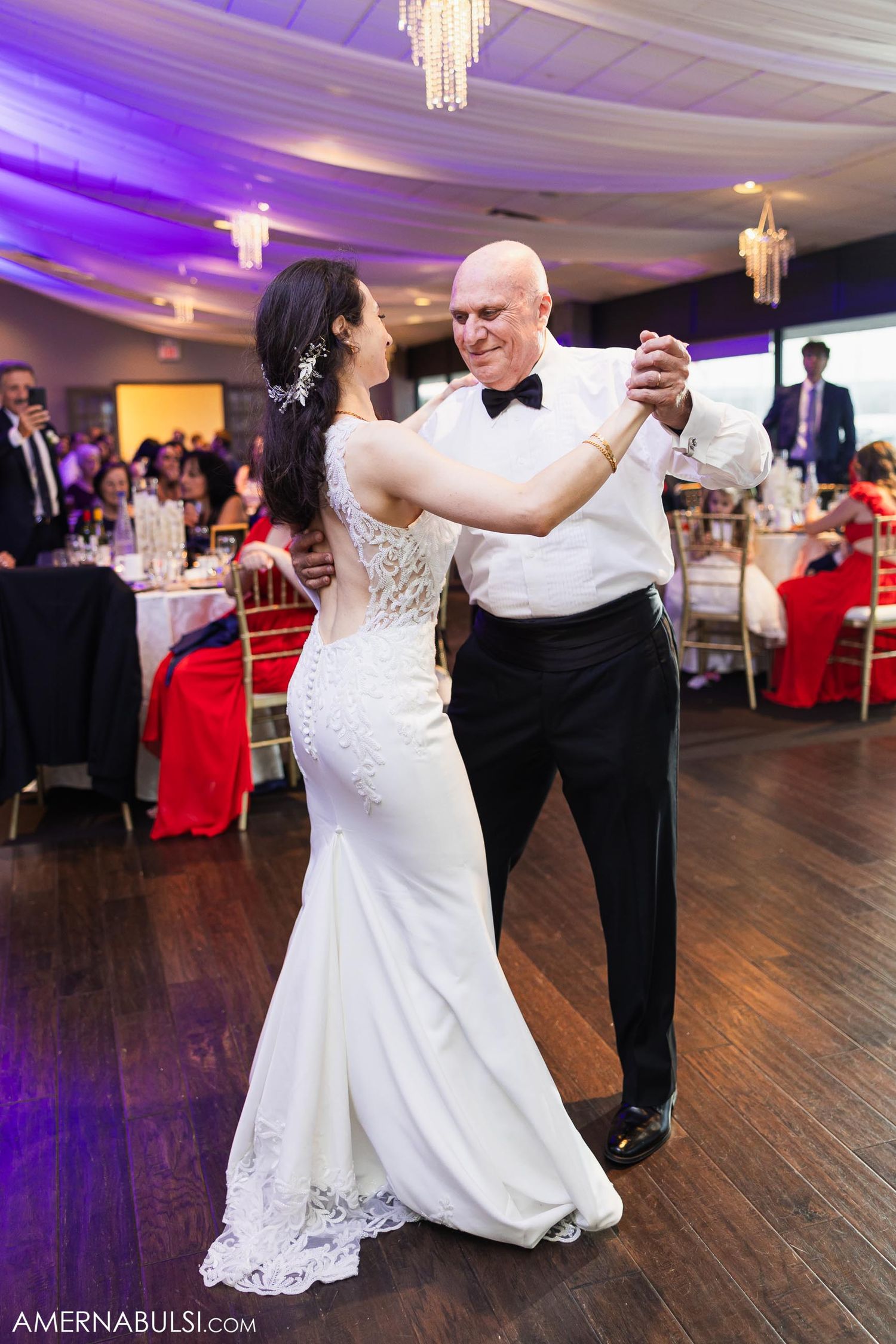 Traditional father-daughter dance at wedding reception with purple uplighting.