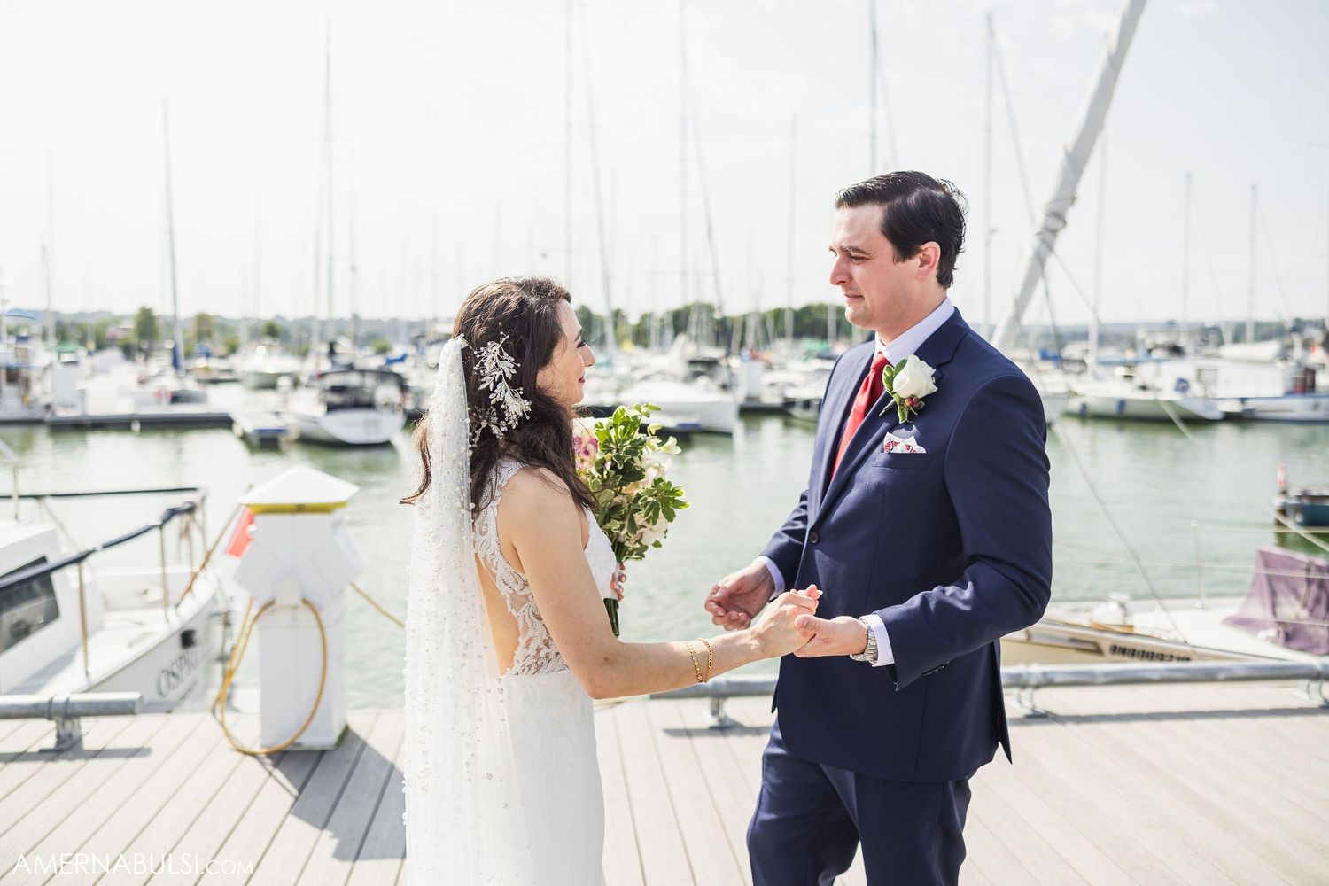 A wedding ceremony moment on a waterfront dock with boats and marina in the background.