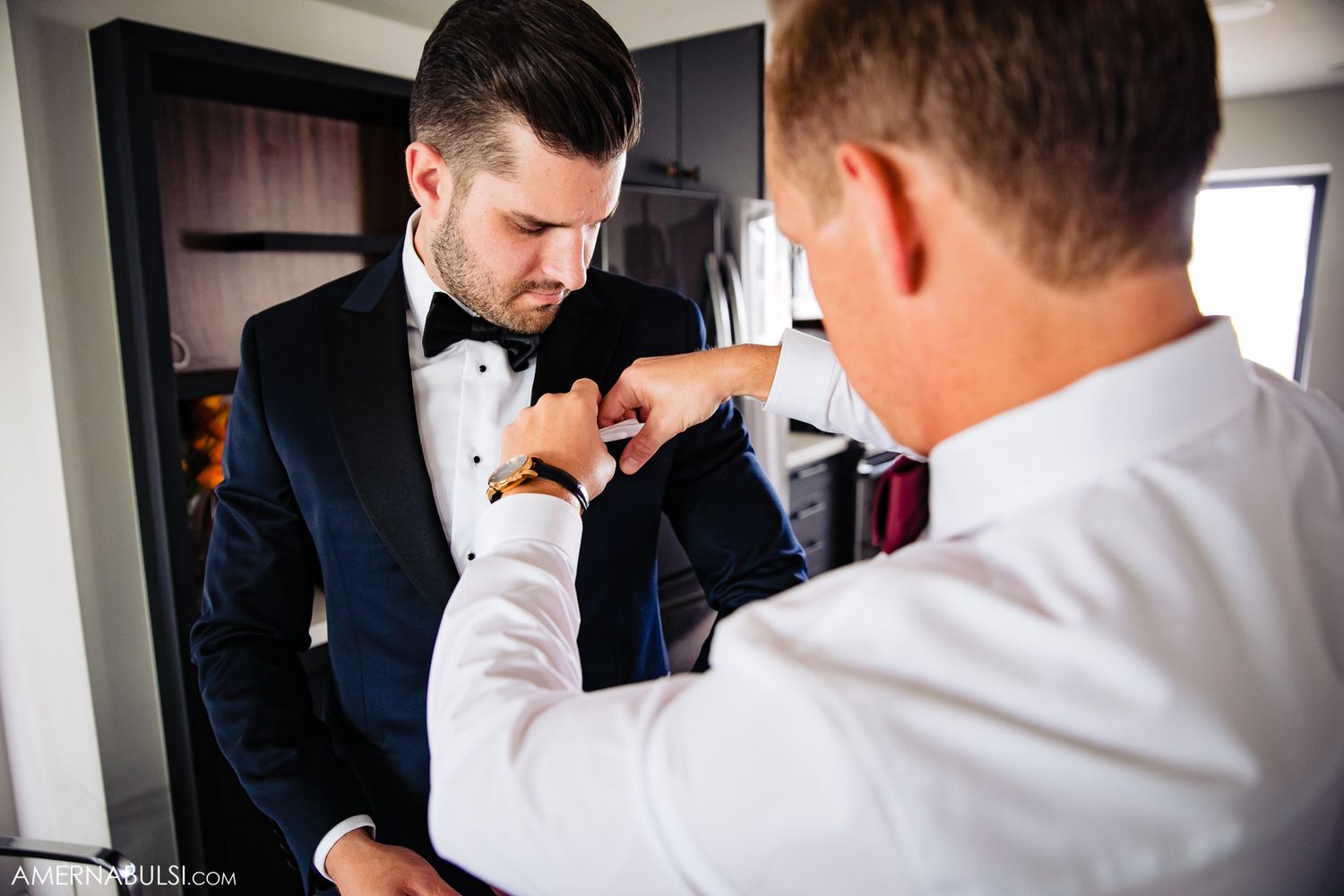 Groomsmen help adjust formal attire before the ceremony.