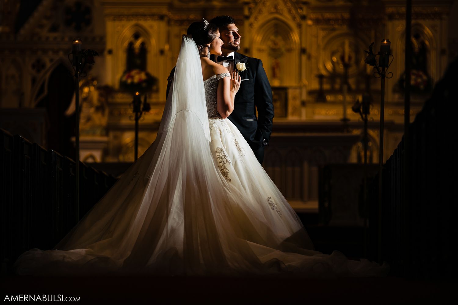 Dramatic silhouette of wedding couple against warm amber lighting in elegant venue.
