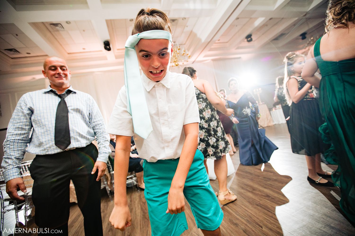 Wedding guests dancing and celebrating on a wooden dance floor at a reception party.