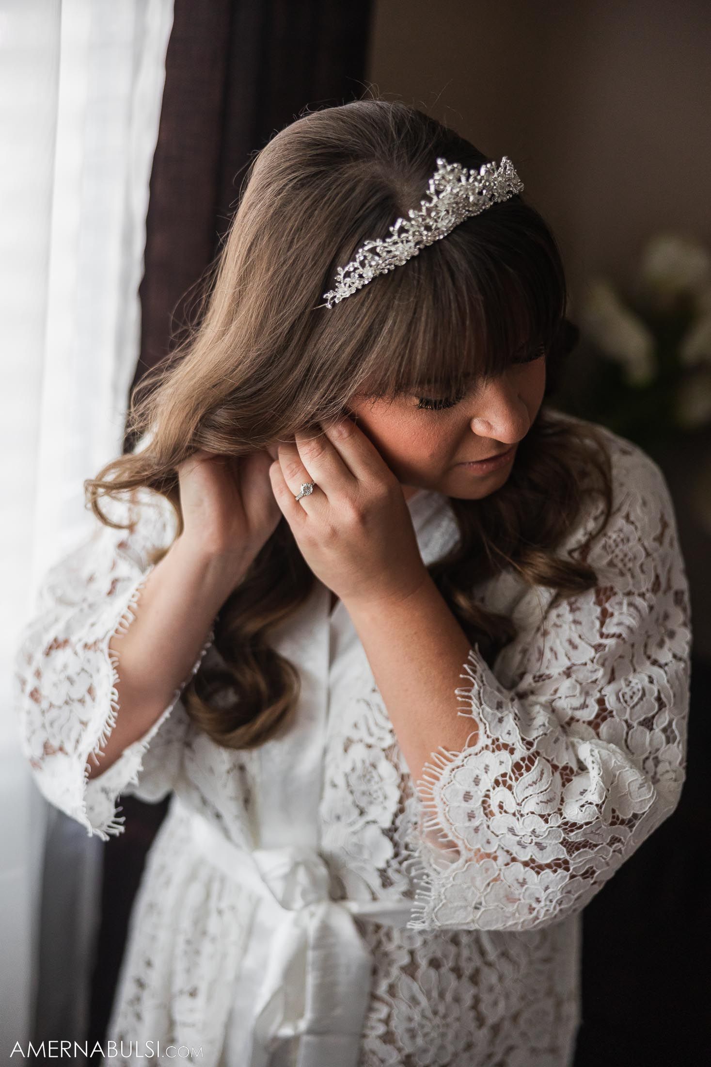 A romantic bridal portrait featuring a crystal tiara and lace robe in soft window light.