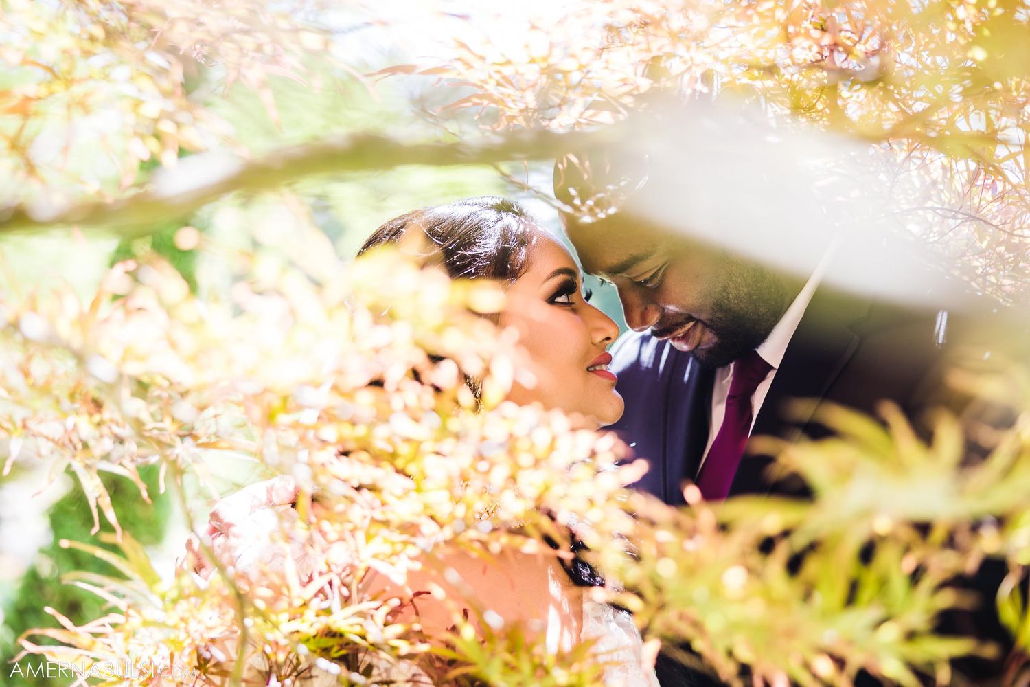 Artistic wedding photo through golden foliage with soft dreamy lighting.