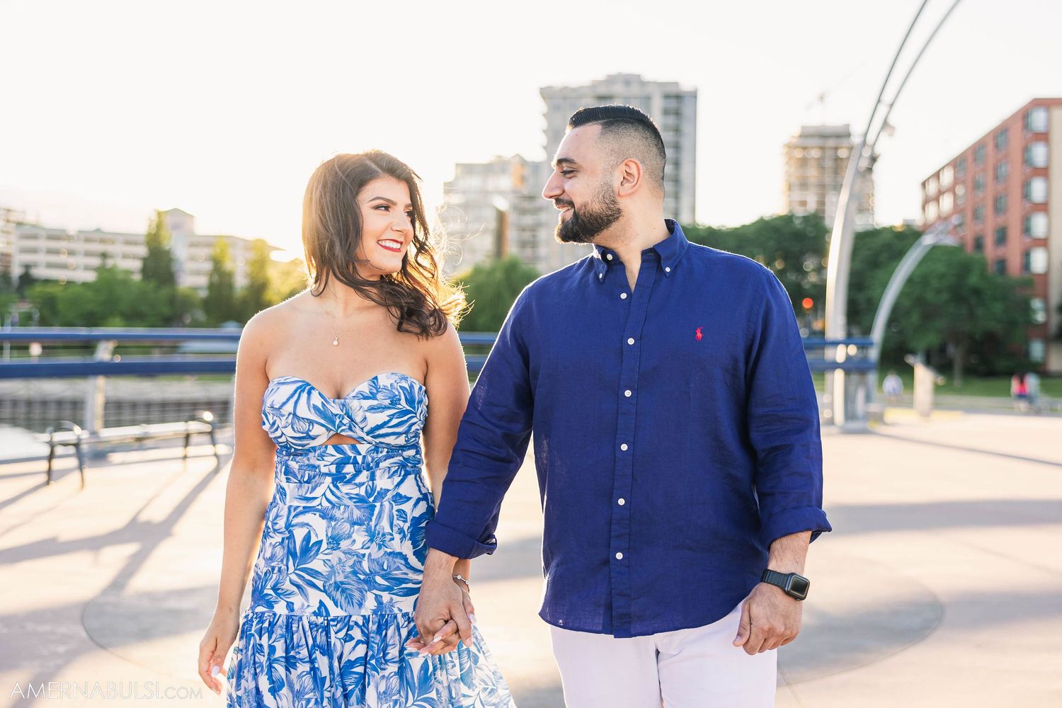 Couple walking together on urban bridge wearing coordinated blue and white outfits.