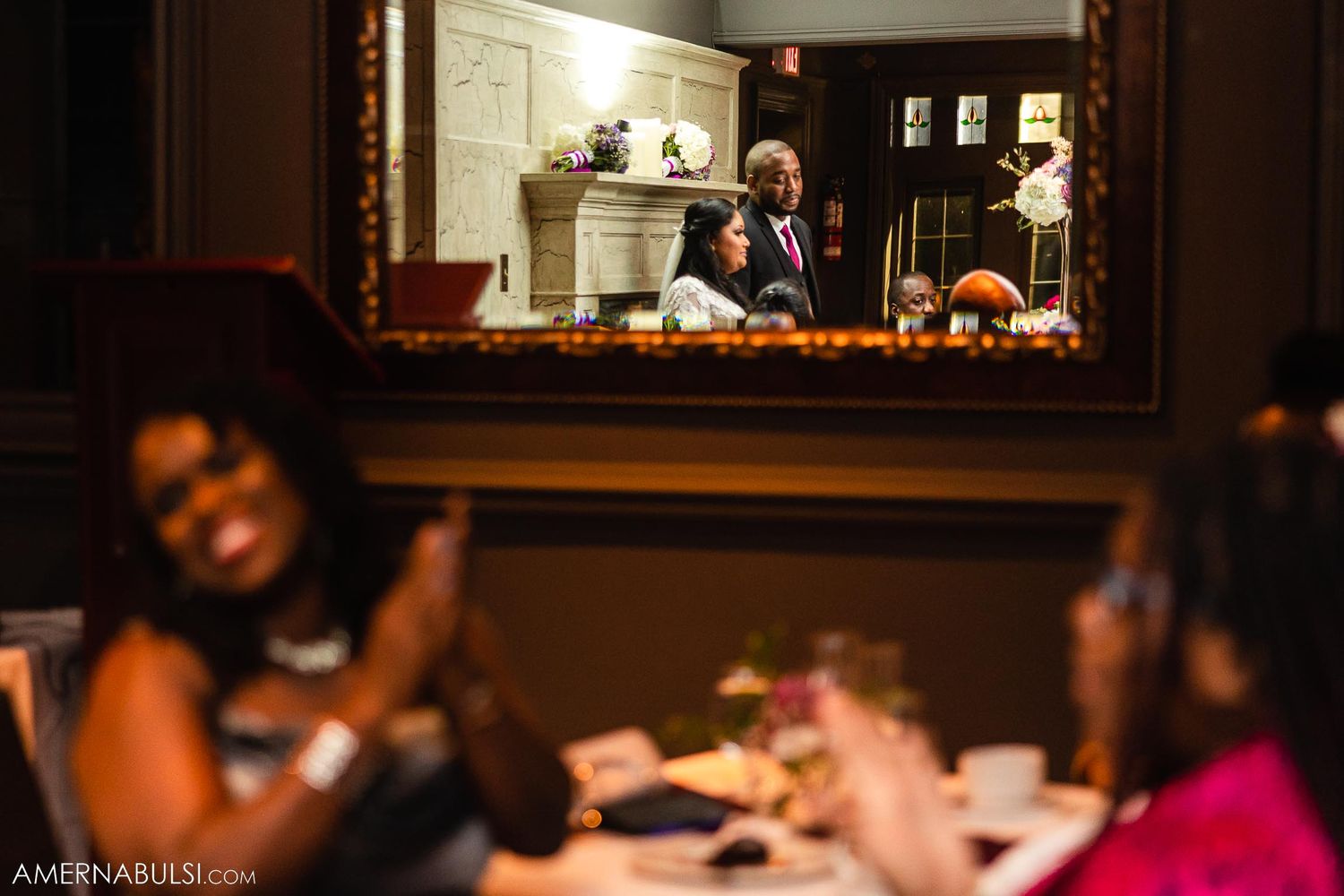 Wedding guests laugh and celebrate during an indoor reception dinner.