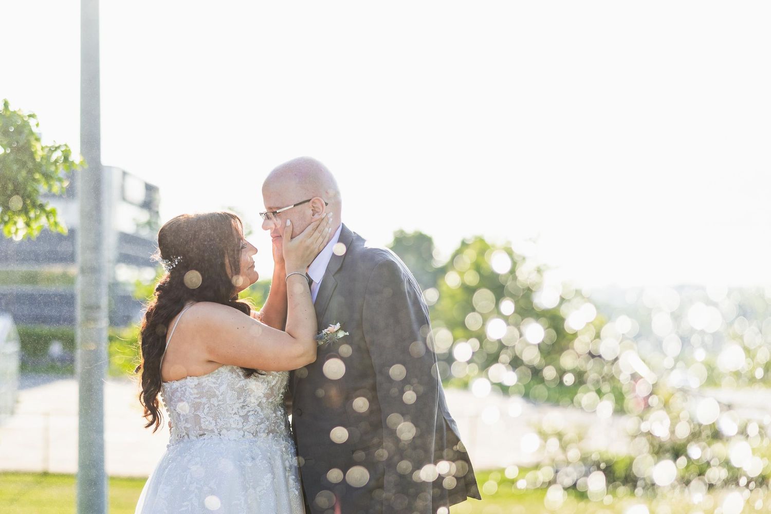 A tender moment between newlyweds against golden sunlight and bokeh.