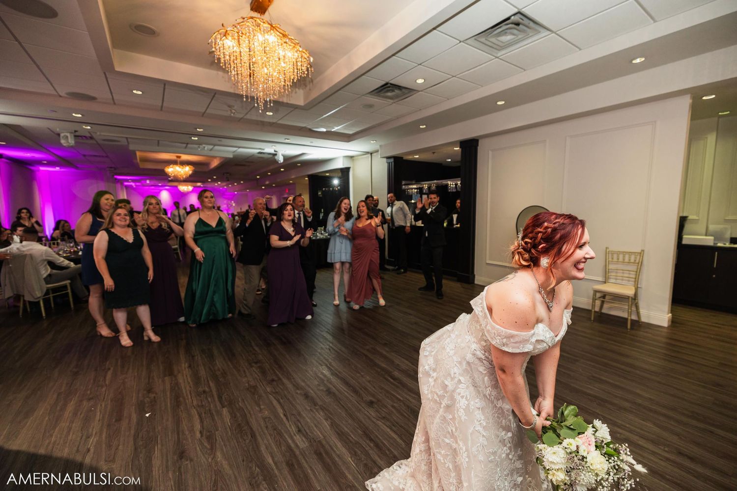 Bride preparing to toss bouquet to waiting guests at wedding reception.