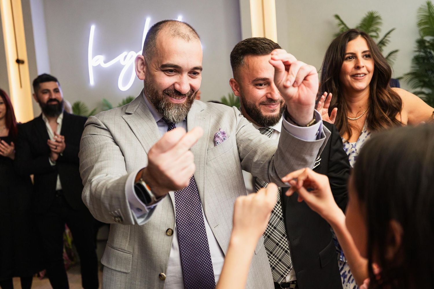 Guests in formal attire share an energetic moment on the dance floor at a celebration.