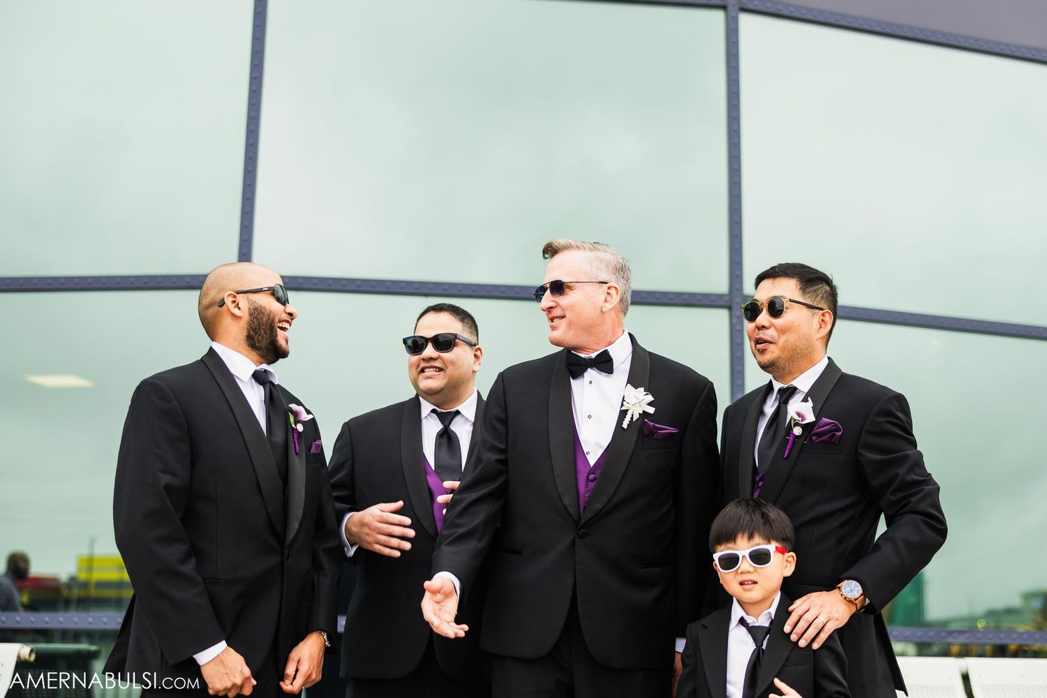 A group of formally dressed people sharing a lighthearted moment outdoors.