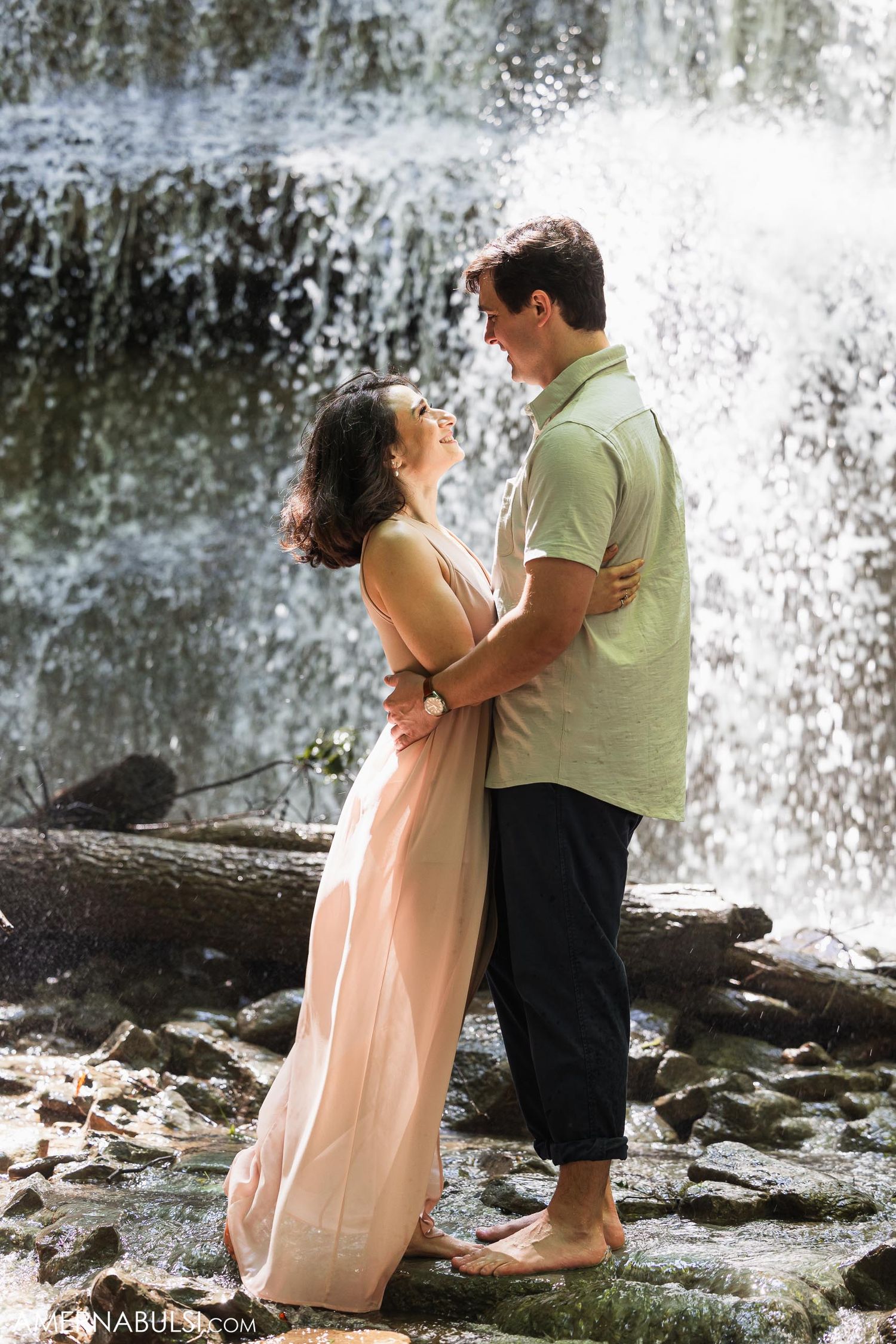 A tender moment shared between two people beside a misty waterfall.