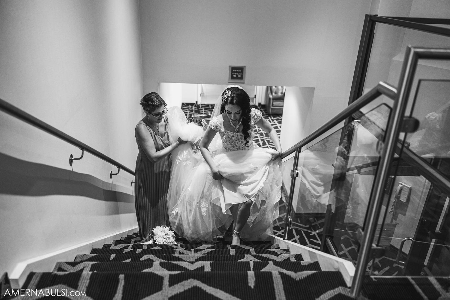 Wedding party celebrates on patterned carpet staircase in black and white photography.