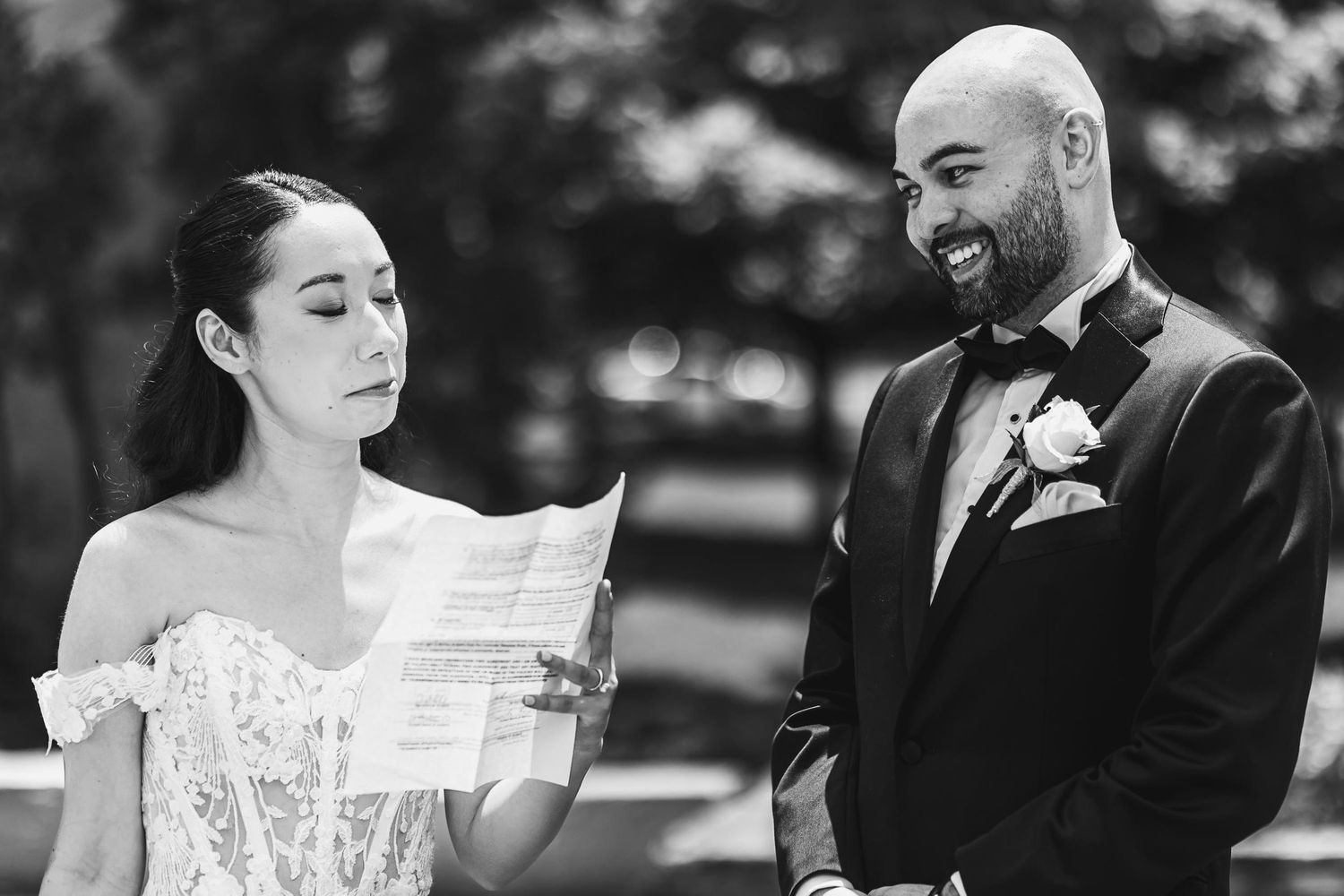 Black and white candid wedding moment showing couple reading a document together.