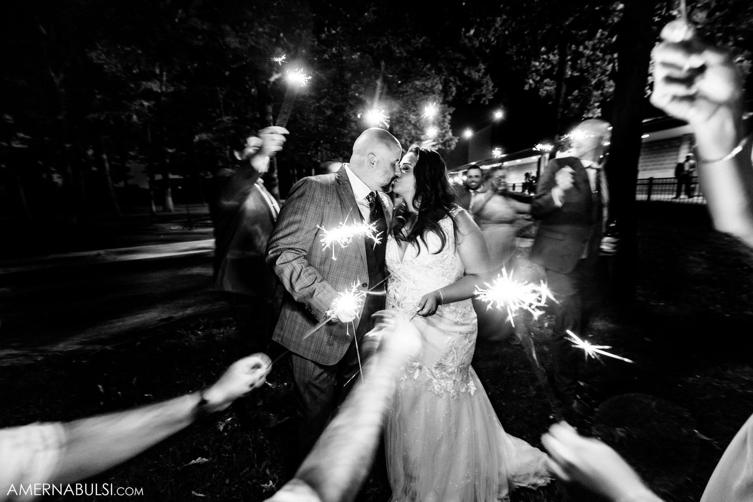 Black and white photo of sparklers lighting up a romantic nighttime wedding celebration.