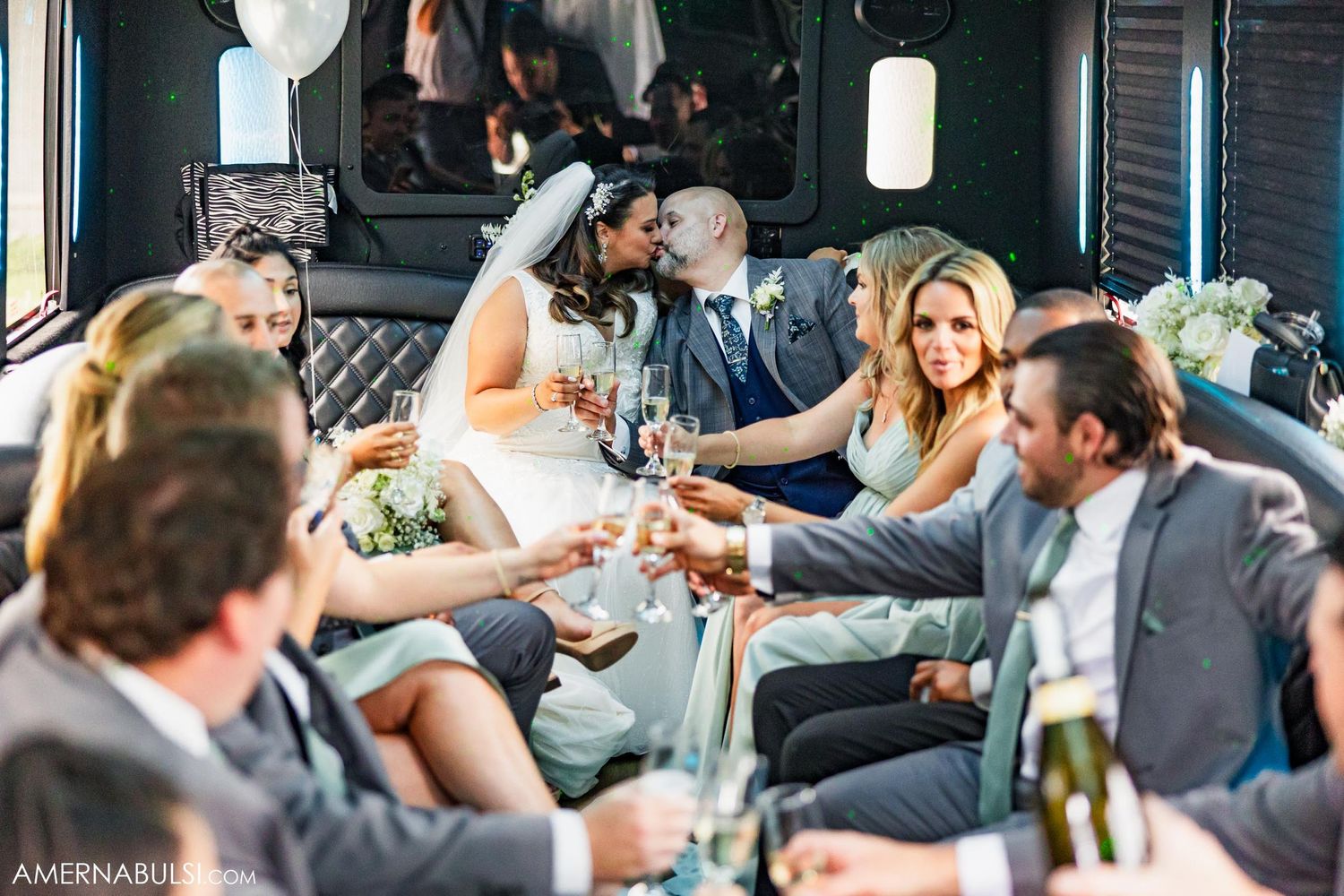 Wedding celebration inside party bus with guests toasting and socializing.