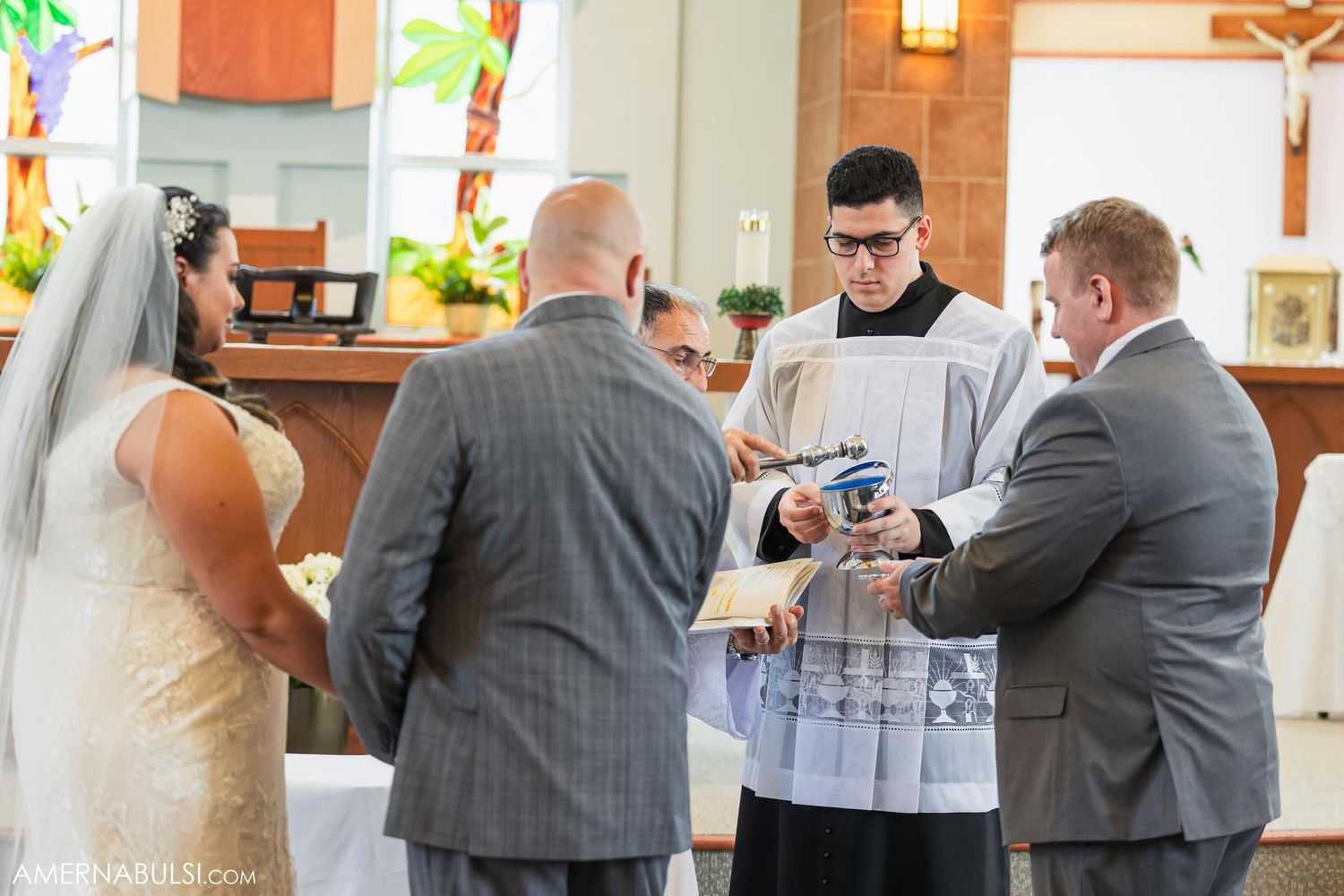 Wedding ring exchange ceremony with officiant and witnesses in church.