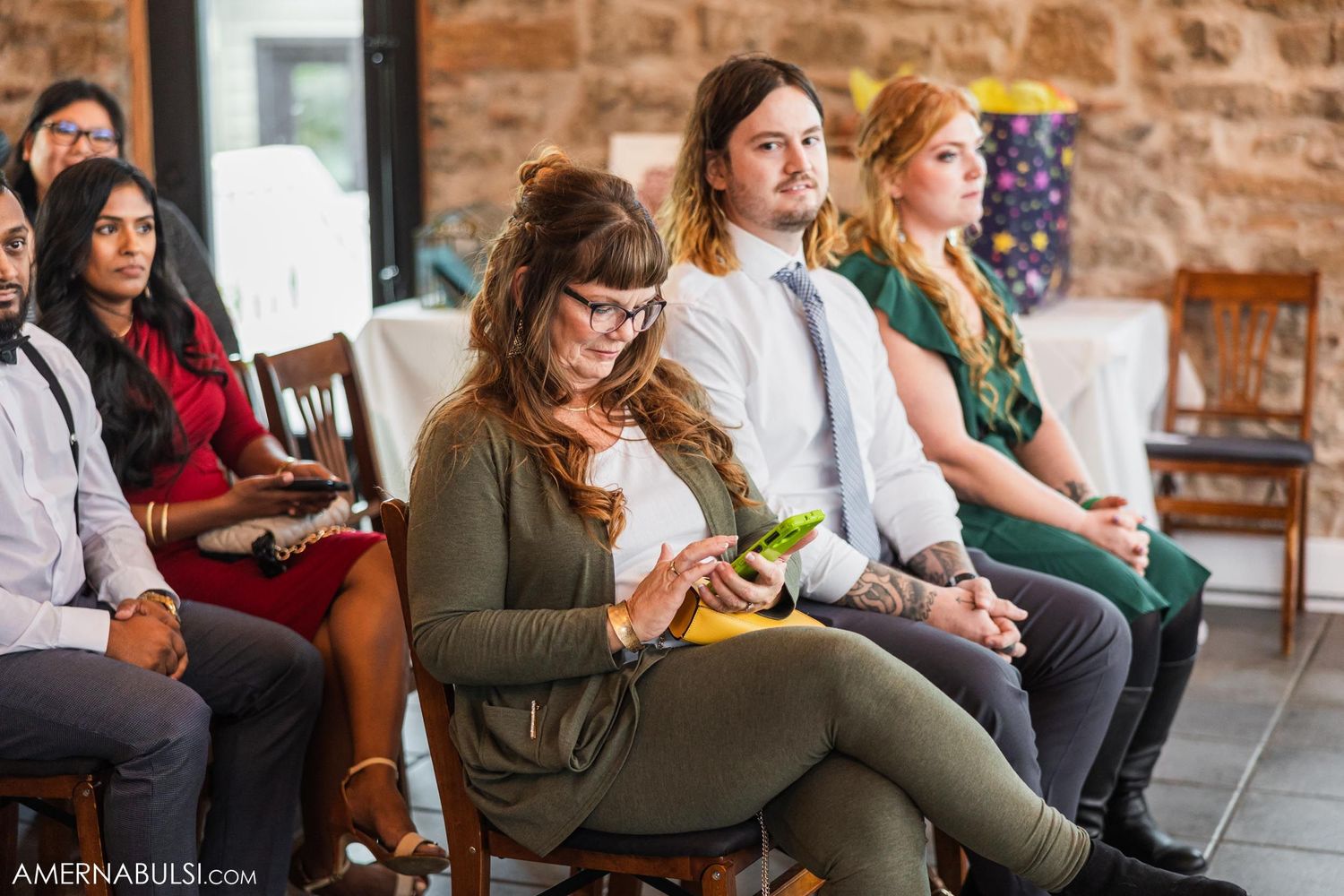 Wedding guests seated in rows inside a rustic stone venue during the ceremony.