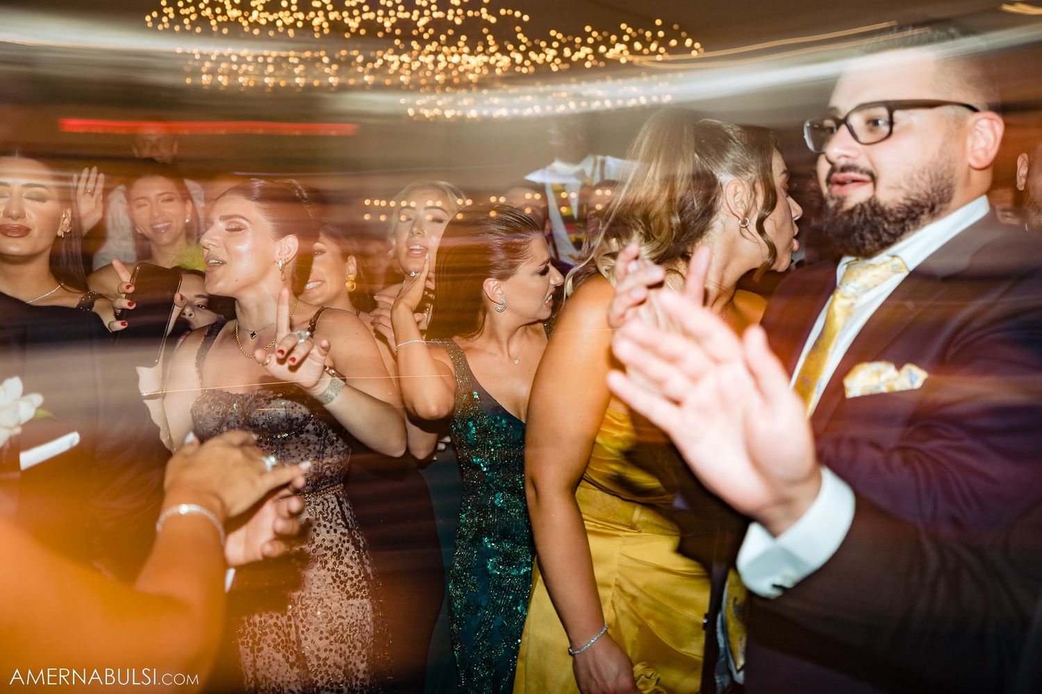 Dynamic party scene with motion blur captures the energy of wedding reception dancers.