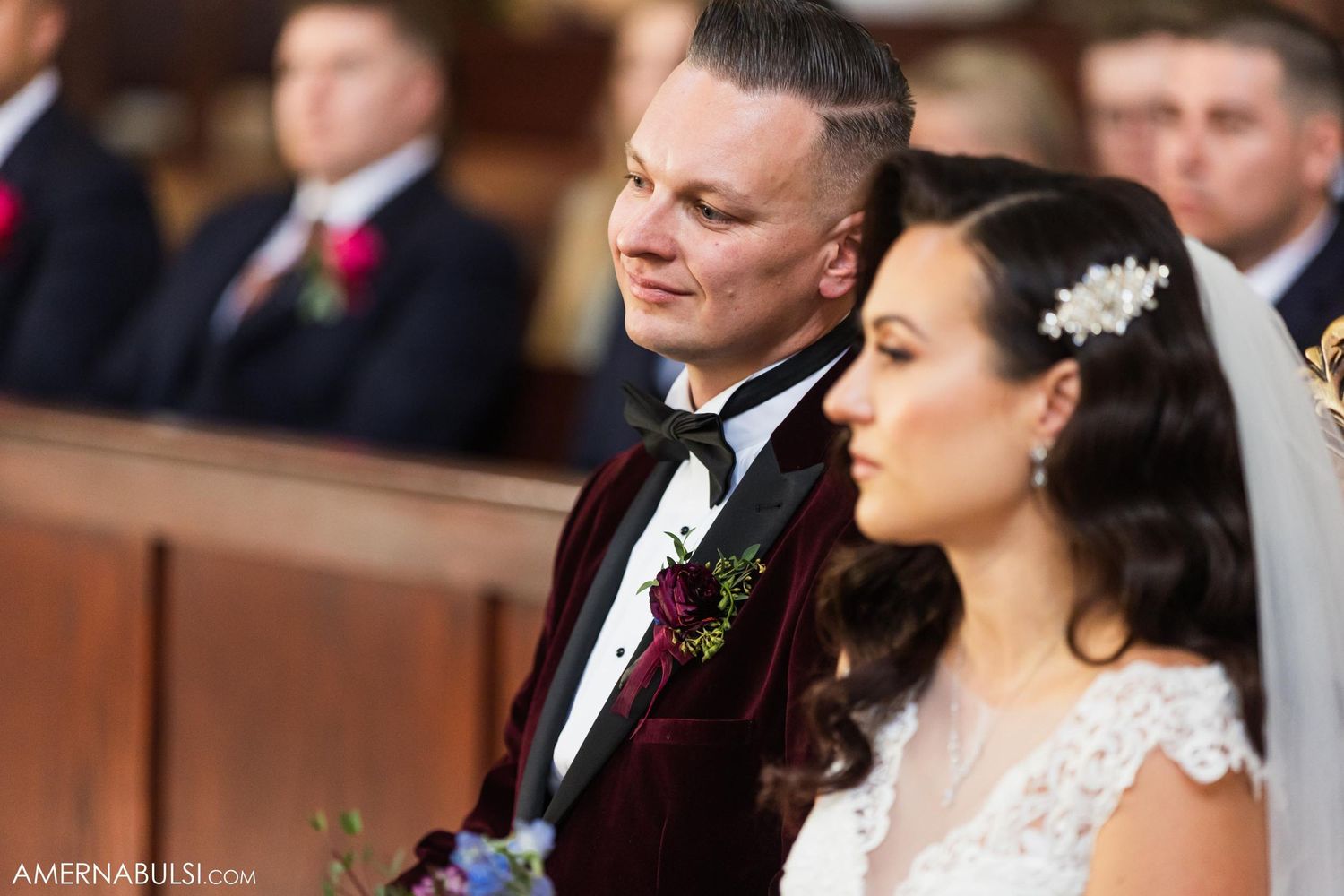 A couple sits together in church pews during their wedding ceremony.