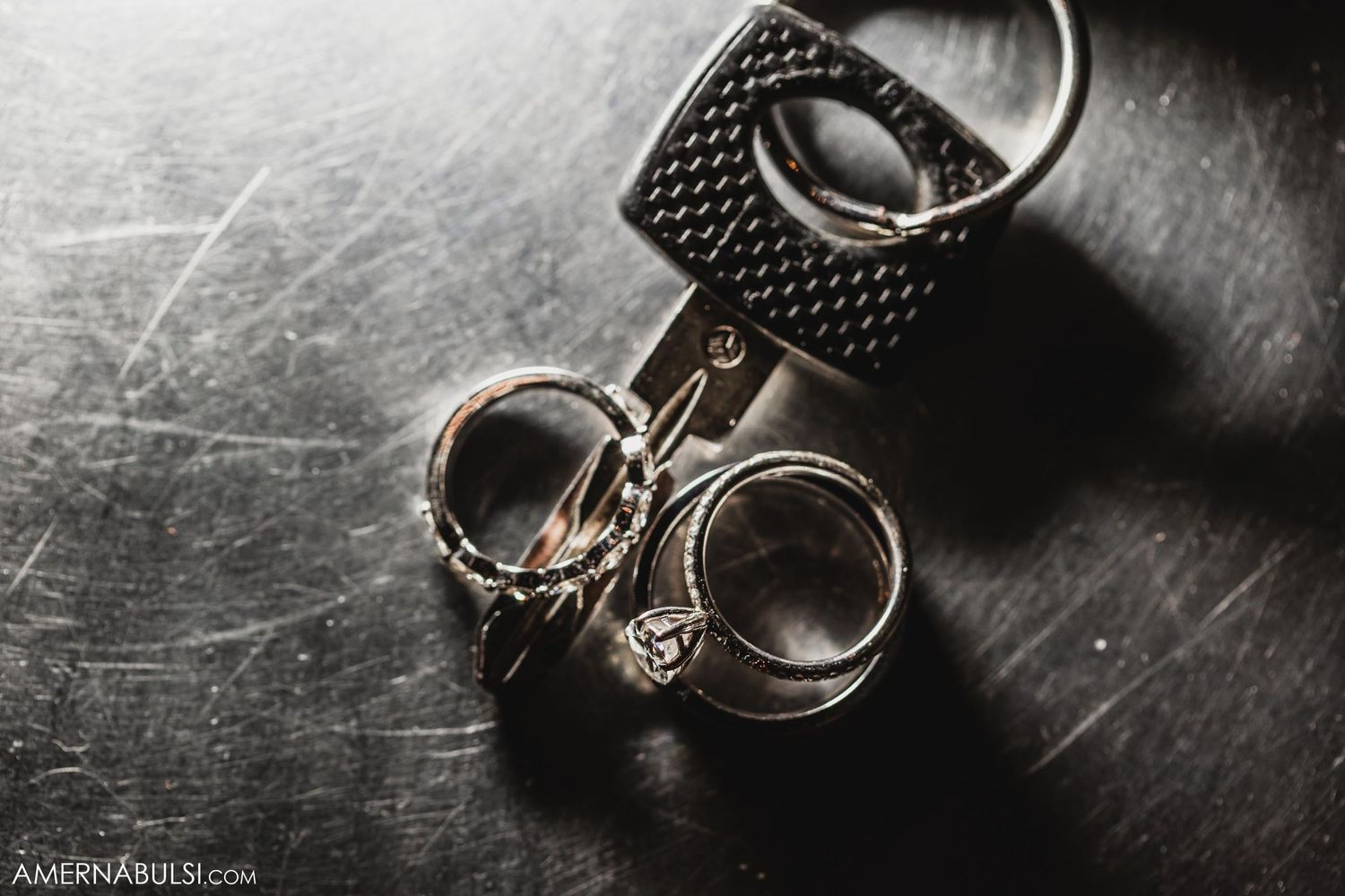Wedding rings and key photographed in dramatic black and white on textured surface.