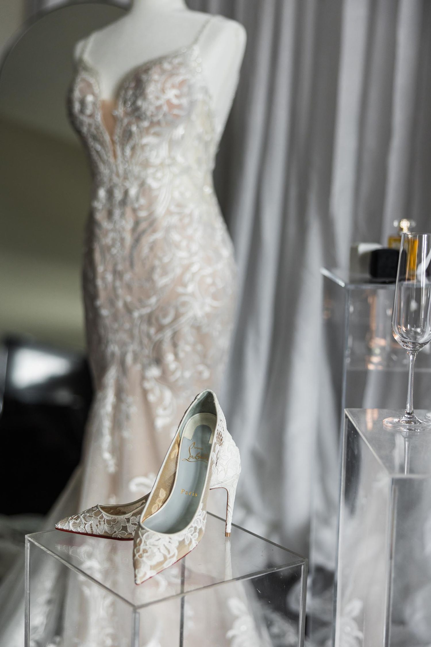 A delicate lace wedding gown displayed with matching heels in an elegant bridal setting.