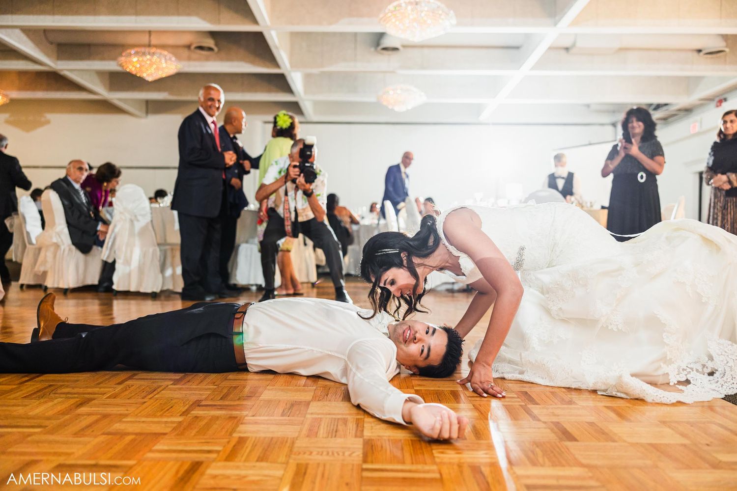 Playful wedding dance move with dramatic dip on the parquet dance floor.