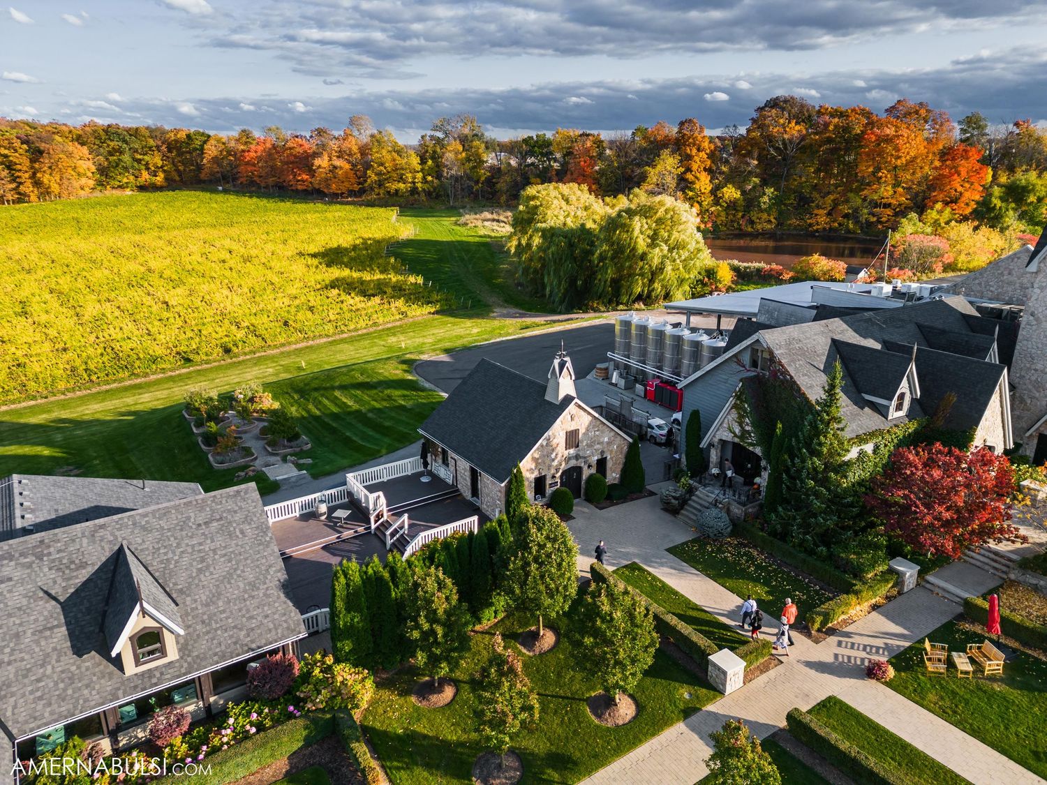 Aerial view of a luxury event venue with black roofs surrounded by autumn trees and green lawns.
