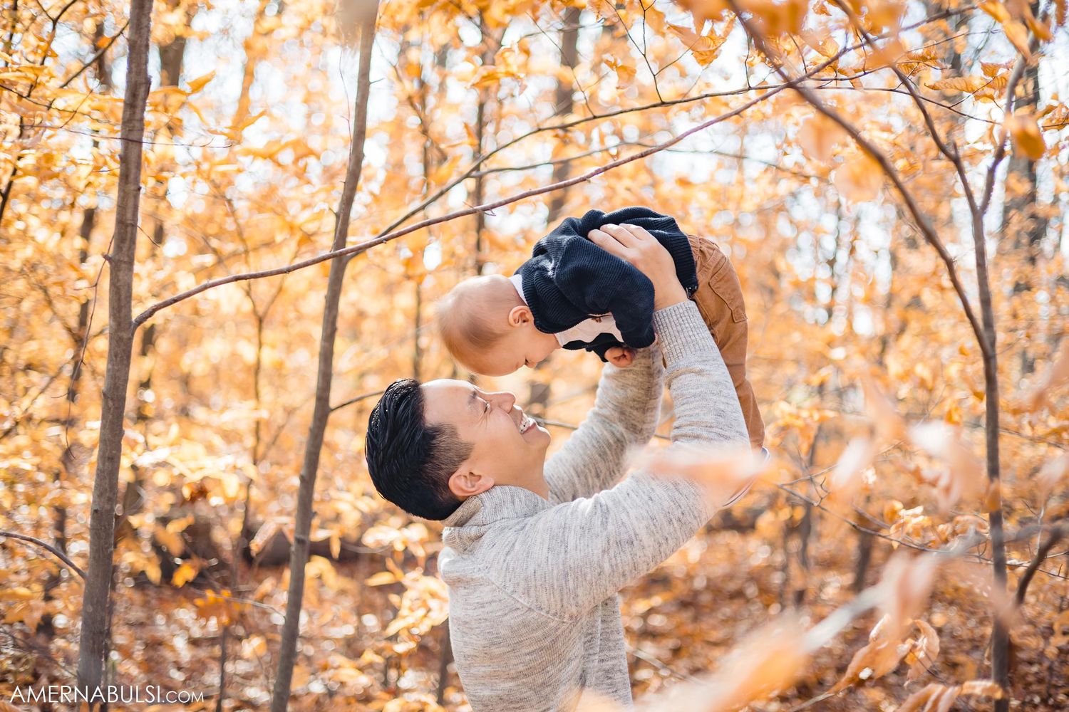 Joyful moment captured in autumn forest with golden sunlight filtering through trees.